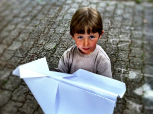 Niño con avión de papel gigante
