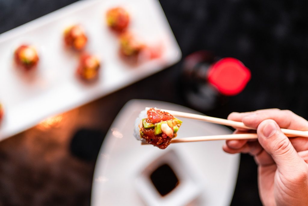 Mano con palillos sujetando un maki